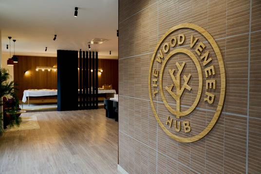Wooden wall with 'The Wood Veneer Hub' logo in a modern interior setting