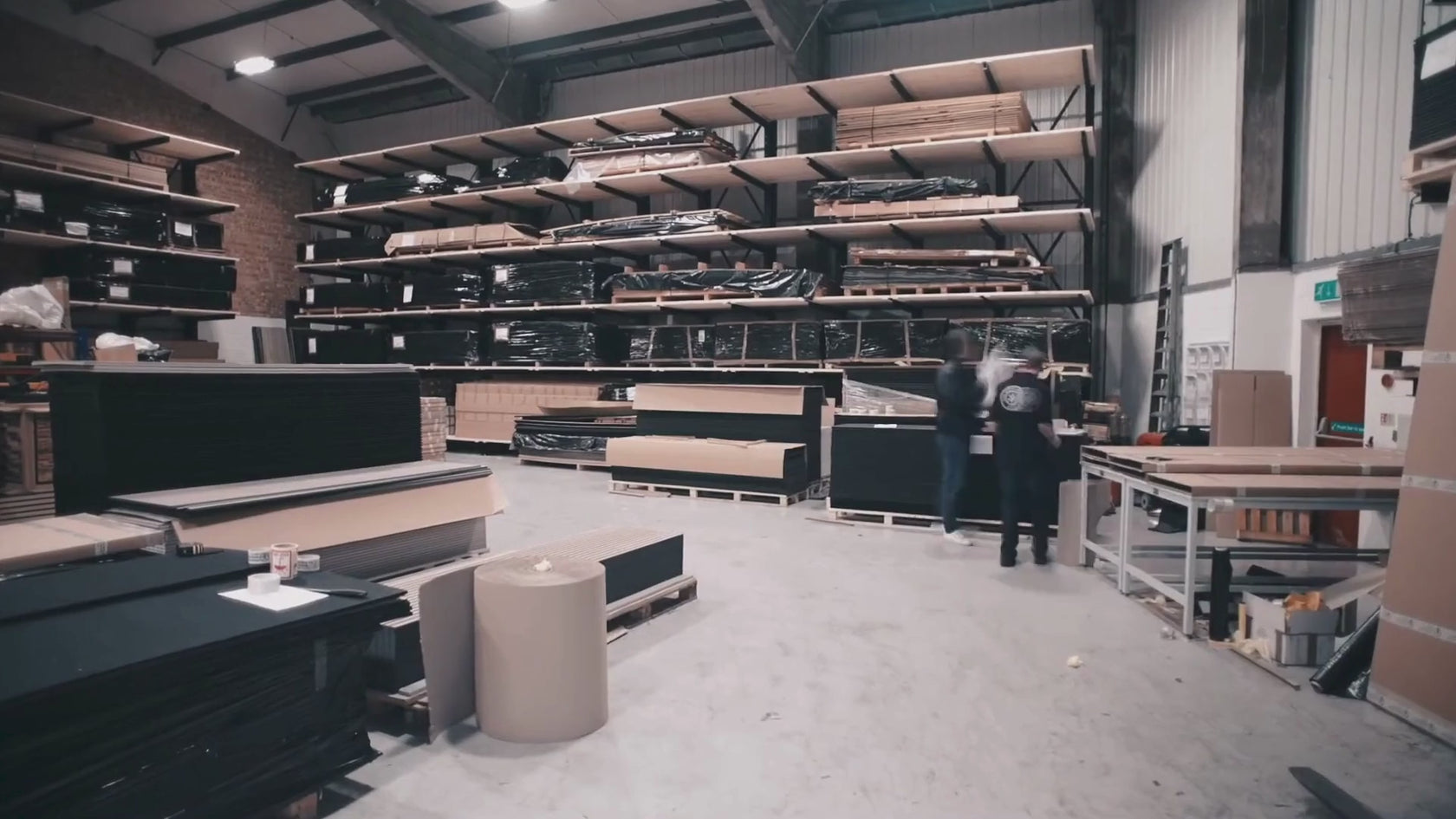 Workers moving around a warehouse and loading a truck with wall panelling ready for dispatch