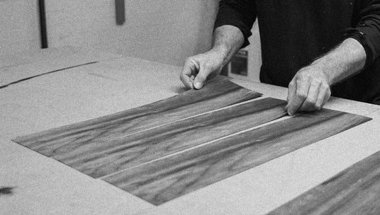 1980s person working with wood veneer on a table (shot in black and white)