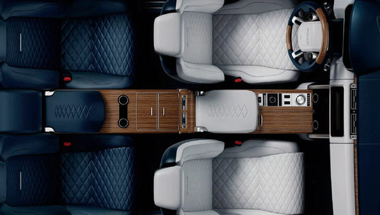 Top-down view of a luxury vehicle interior with quilted seats and wooden veneer dashboard.